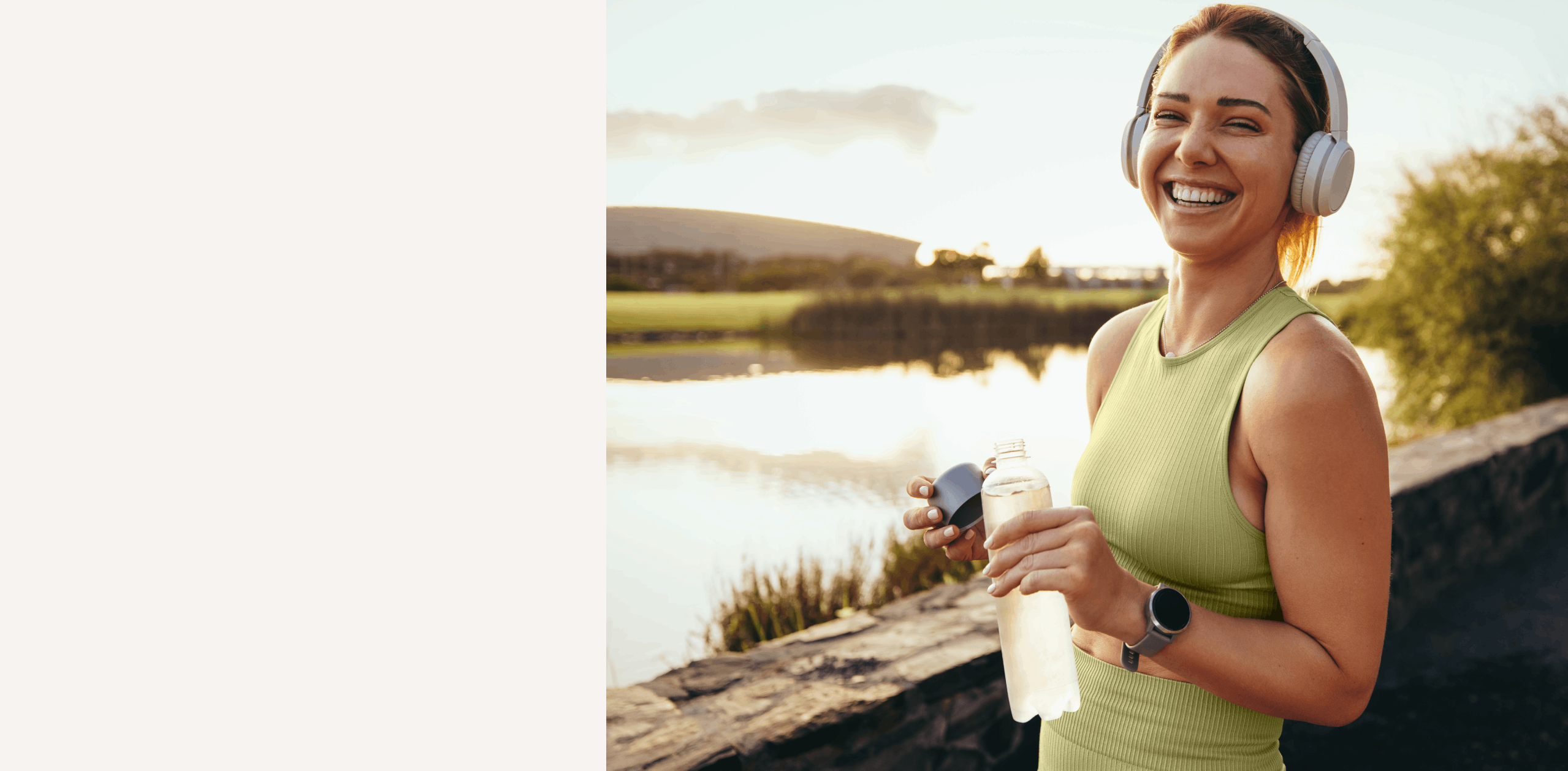 Woman outdoors after exercise, holding a water bottle and smiling by a lake.